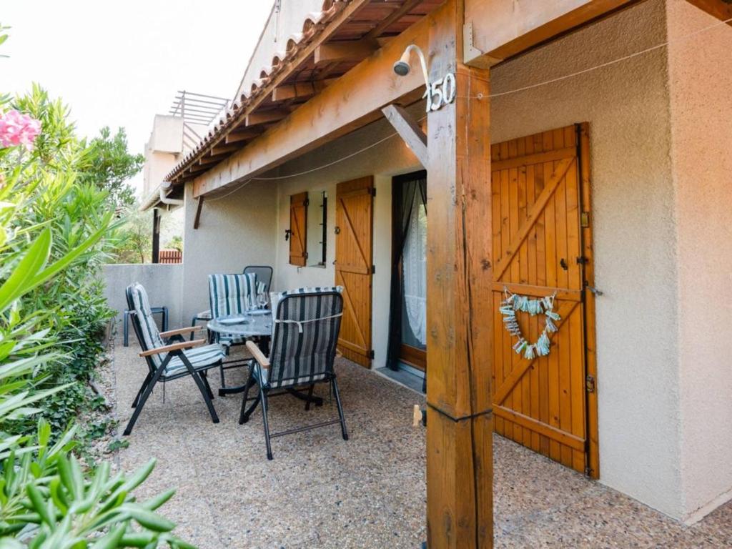 une terrasse avec une table et des chaises à côté d'une maison dans l'établissement Pavillon T2 Mezzanine climatisé, piscine, Wifi, proche lagune et plage, parking, non-fumeur - FR-1-409-237, à Gruissan