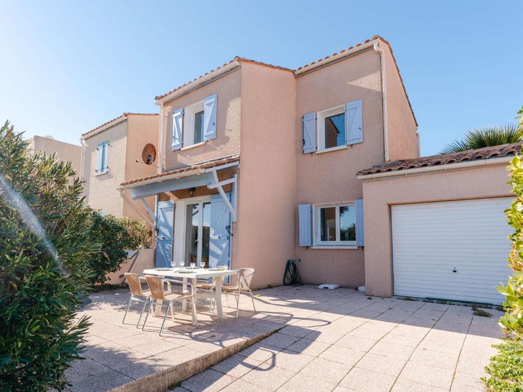 una casa con un tavolo e sedie di fronte di Pavillon Confortable avec Piscine, Terrasse et Parking Privé - FR-1-409-220 a Fleury