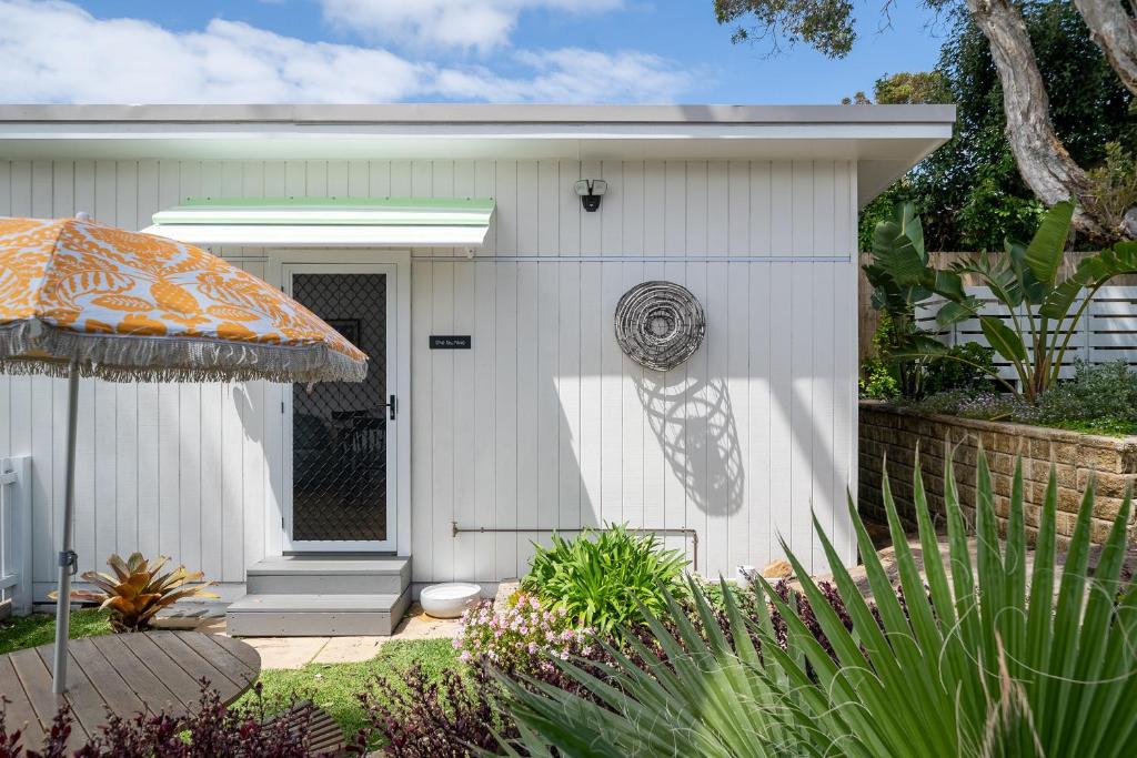 una casa blanca con un paraguas naranja delante de ella en The Bunkie @ Ethel & Odes, en Bundeena