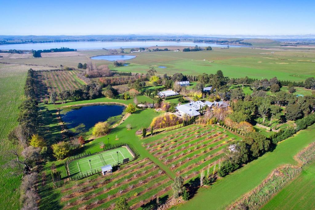 an aerial view of a farm with a house and a lake at Orchards at Spring Vale Farm in Weatherboard