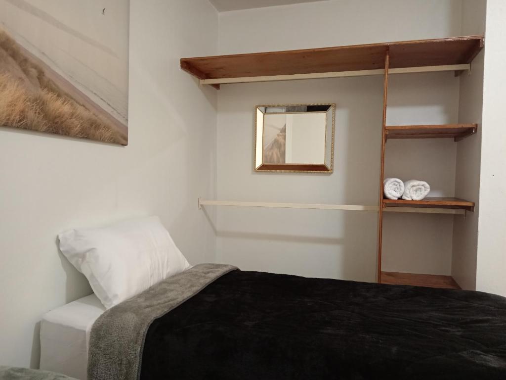 1 dormitorio con cama, espejo y estante en Hospedaje La Gloria, en Texcoco de Mora