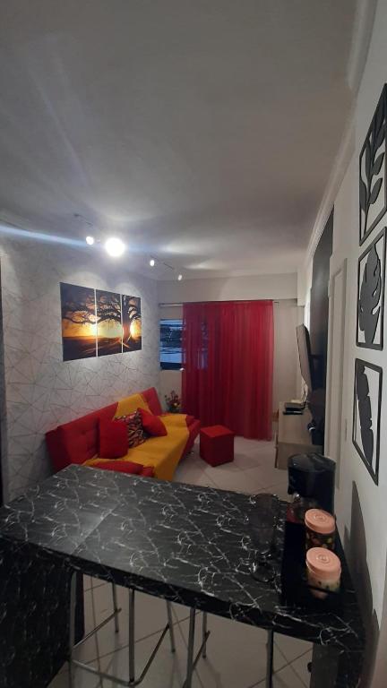 a living room with a table and a yellow couch at Milton Bandeira flat in Viçosa