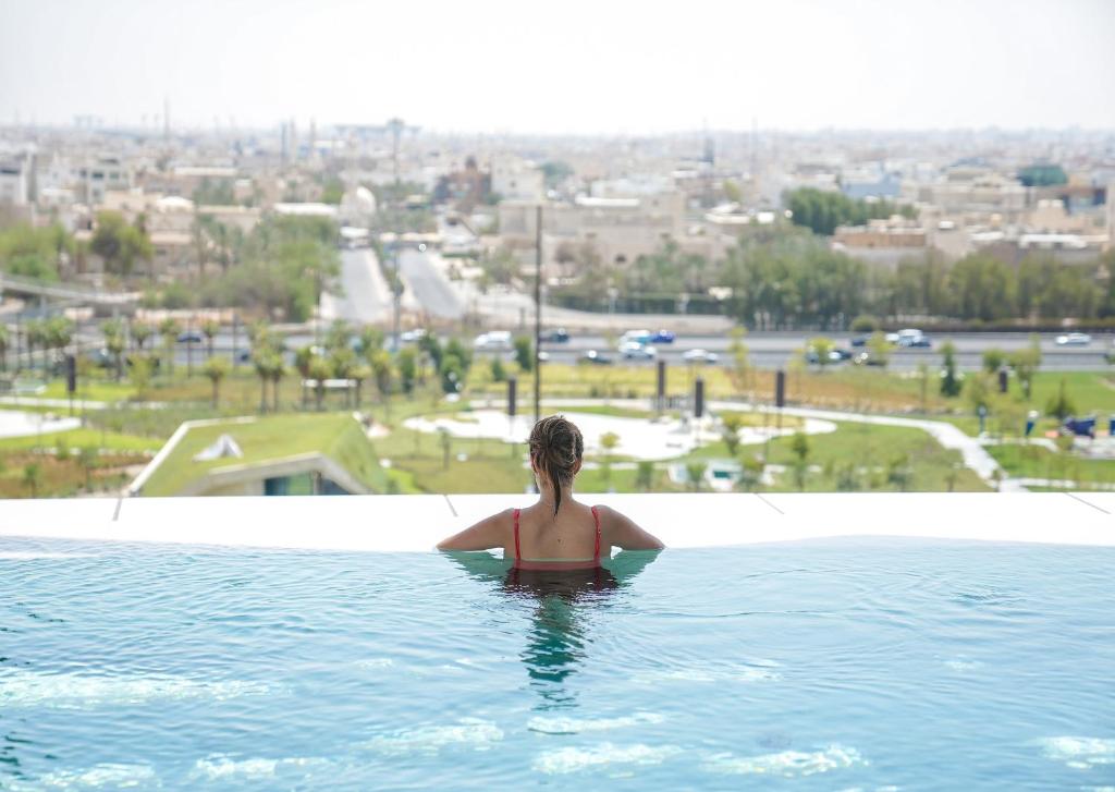 a woman in a swimming pool looking at a city at Four Seasons Hotel Kuwait at Burj Alshaya in Kuwait