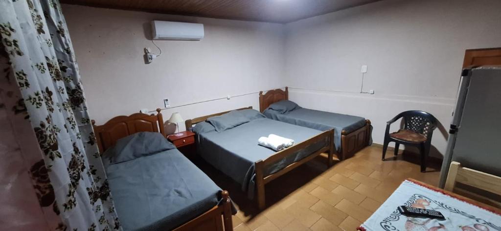 Habitación pequeña con 2 camas y silla en Raquel alojamiento en Puerto Iguazú