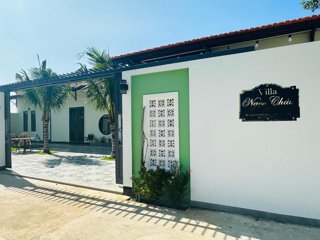 een wit en groen gebouw met een bord erop bij Villa Ngọc Châu Phan Thiết Chi nhánh 2 - 4 Phòng Ngủ, Có Bếp, Phòng Ăn, Phòng Khách, Miễn Phí Sân BBQ và Bãi Xe Ô Tô Rộng Rãi in Phan Thiet