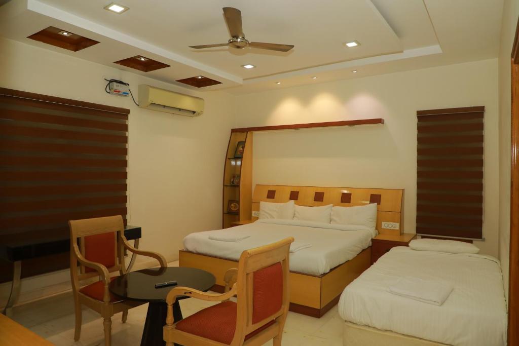 a bedroom with two beds and a table and chairs at Hill View Paradise Villa - duplex with private theater & 2bhk - A Golden Group Of Premium Home Stays - tirupati in Tirupati