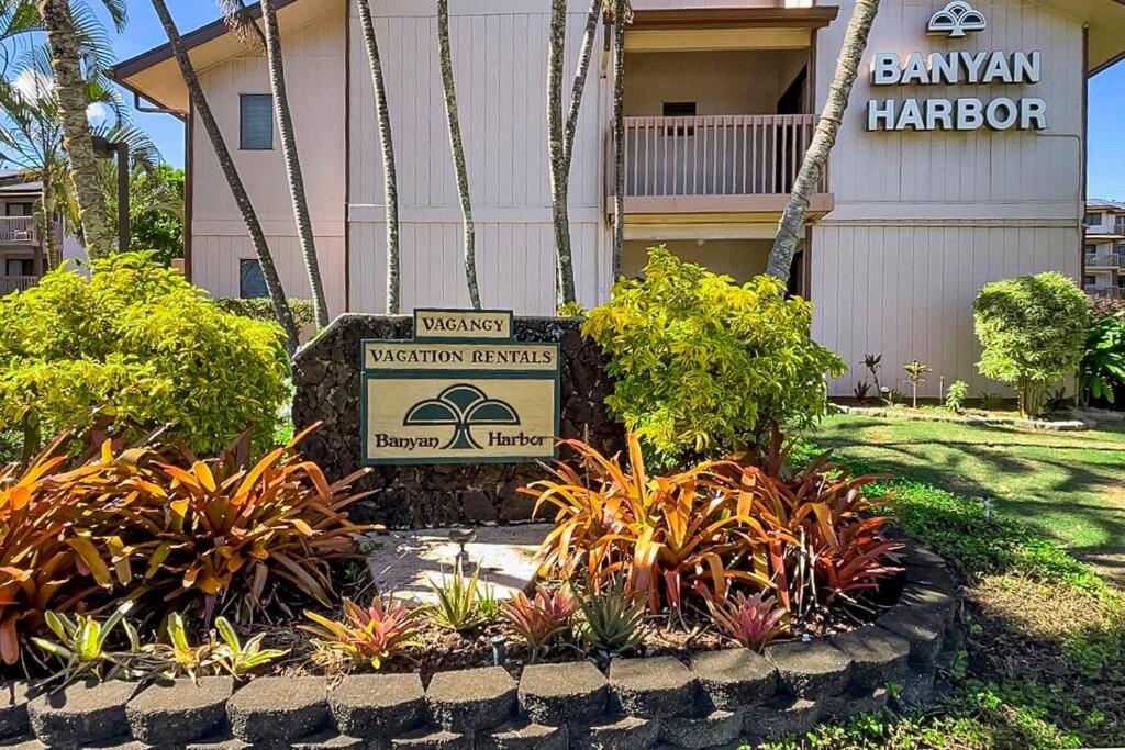 a sign in front of a building with plants at Ground floor Banyon Harbor in Lihue