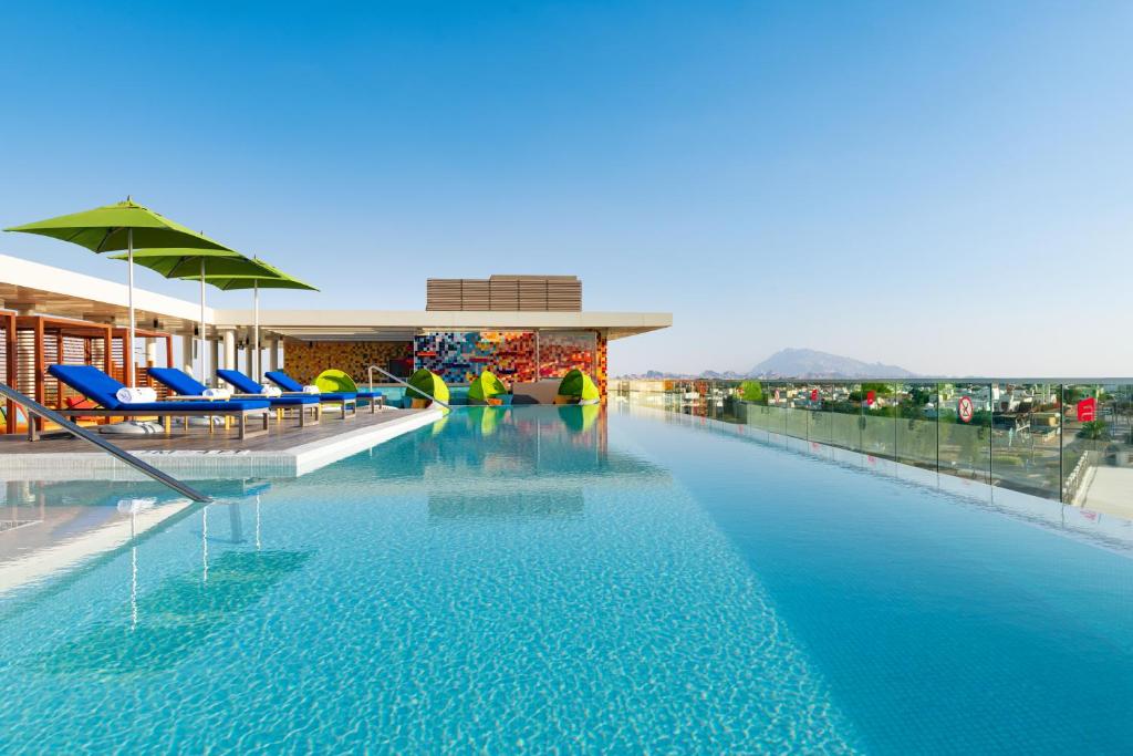 a swimming pool with blue chairs and a building at Aloft Al Ain in Al Ain