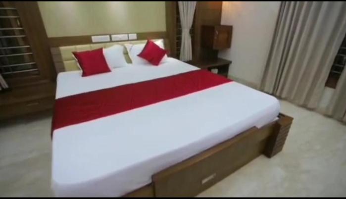 1 dormitorio con 1 cama grande con almohadas rojas en Shoolin Palace, en Mangalore