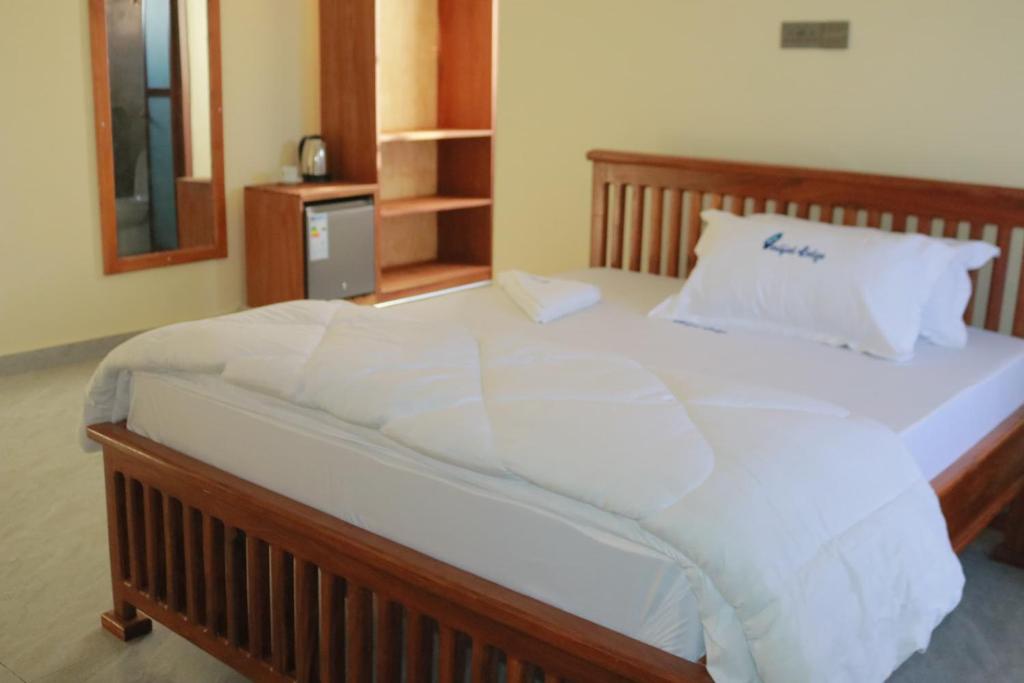 duże łóżko z białą pościelą i poduszkami w obiekcie Verified Lodge w Dodomie