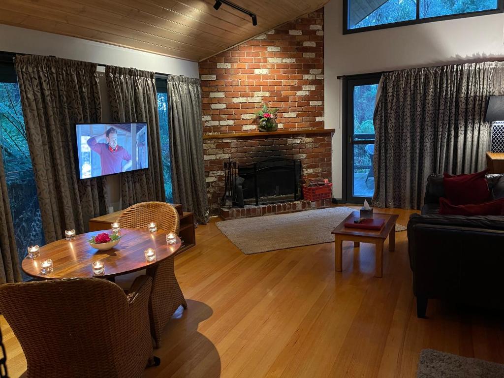 a living room with a table and a fireplace at Woodlands rainforest retreat in Narbethong