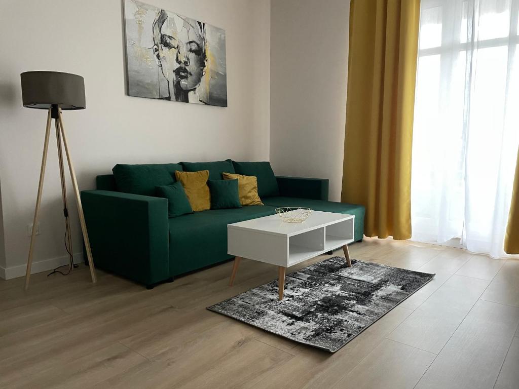 a living room with a green couch and a table at Apartament Pirat in Ostróda