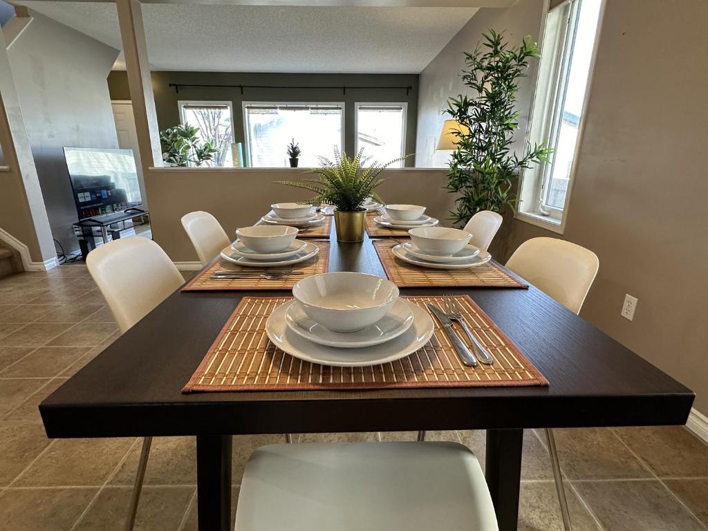 a dining room with a table with plates and bowls at Spacious & Private Retreat near West Edmonton Mall in Edmonton