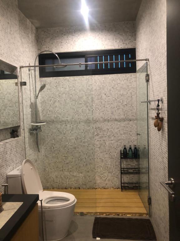 La salle de bains est pourvue de toilettes et d'une cabine de douche en verre. dans l'établissement T House Cha-Am, 