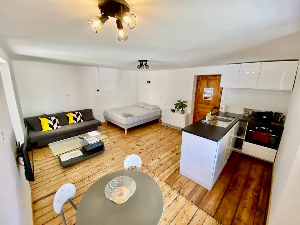 ein kleines Wohnzimmer mit einem Tisch und einer Küche in der Unterkunft Grand studio classé 4 étoiles avec jardin et garage vélo, moto in Briançon
