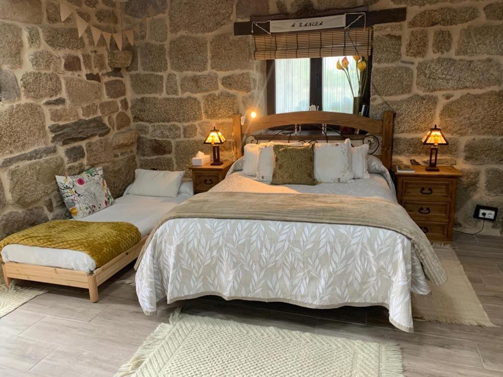 a bedroom with two beds and a stone wall at A XANELA 