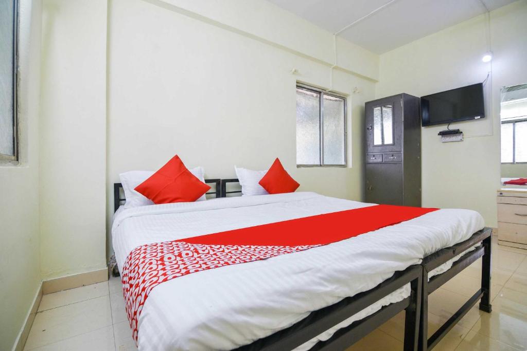 a bedroom with a large bed with red pillows at Hotel O Pratikruti Resort in Pune