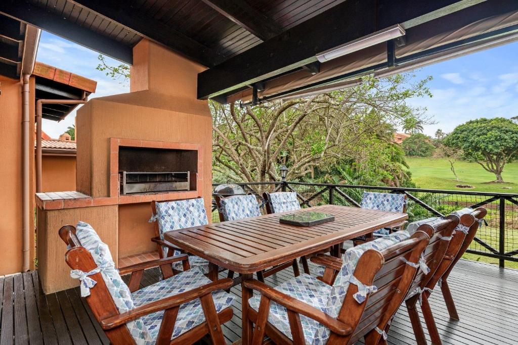 una mesa de madera y sillas en una terraza en San Lameer Villa 2704 - 4 Bedroom Classic - 8 pax - San Lameer Rental Agency, en Southbroom