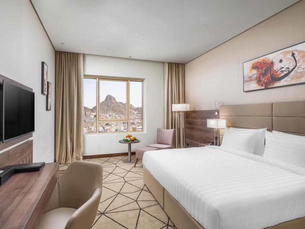 メッカにあるWirgan Hotel Al Nourのベッドとテレビが備わるホテルルームです。
