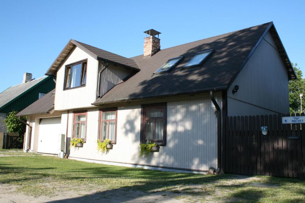 una casa blanca con techo negro en Guest House Viga, en Pāvilosta