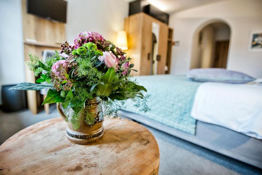 Historisches Gasthaus Hotel Hirschen Horn في غاينهوفن: إناء من الزهور على طاولة في غرفة النوم
