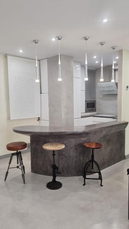 a kitchen with a counter with two stools and a table at SARDINERO in Santander