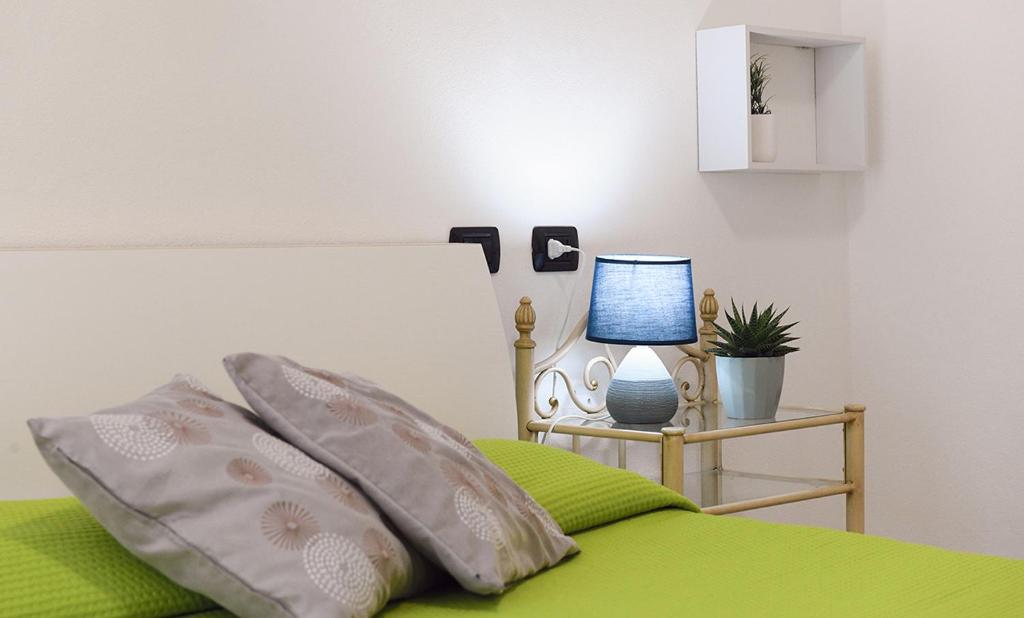 una camera da letto con un letto con lenzuola verdi e una lampada di KRIS87 A 5 Minuti dal Porto ad Alghero