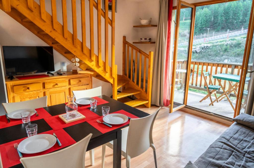 une salle à manger avec une table, des chaises et une télévision dans l'établissement Résidence Les Terrasses Du Soleil D'or - Agréable duplex avec vue sur les pistes MAE-4534, aux Orres
