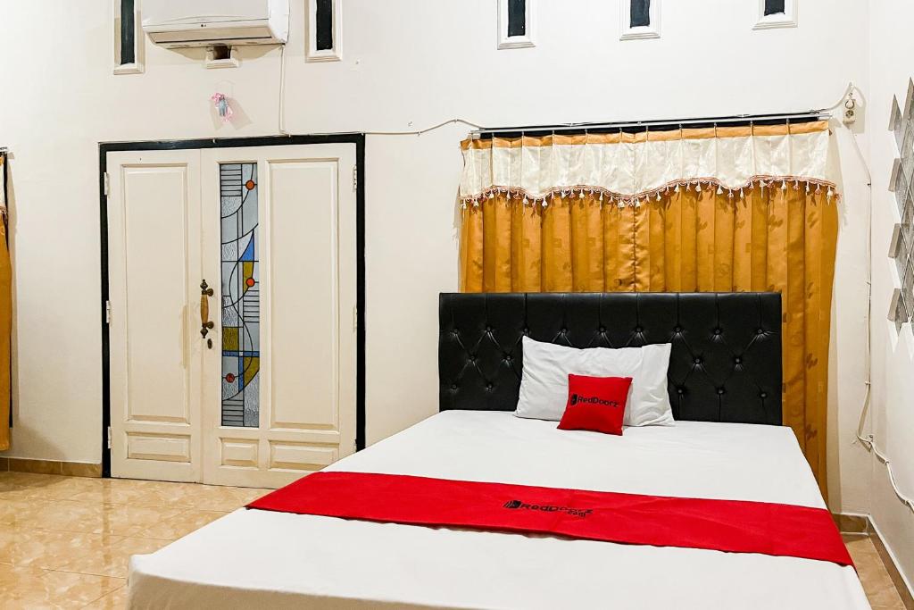 a bedroom with a bed with a red pillow at RedDoorz Syariah At Santana Stasiun Kepanjen in Malang