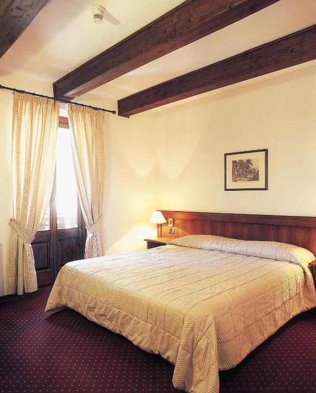 a bedroom with a large bed and a window at Hotel Dei Camosci in Courmayeur