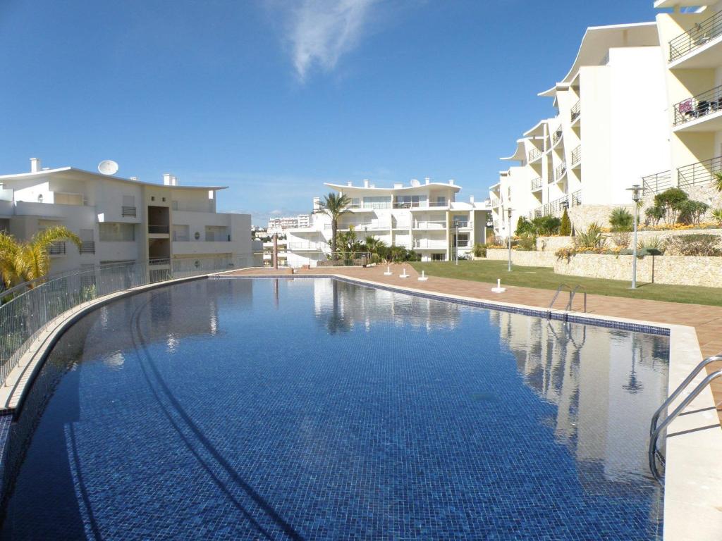 une grande piscine en face de certains bâtiments dans l'établissement Apartament Encosta Da Orada, à Albufeira