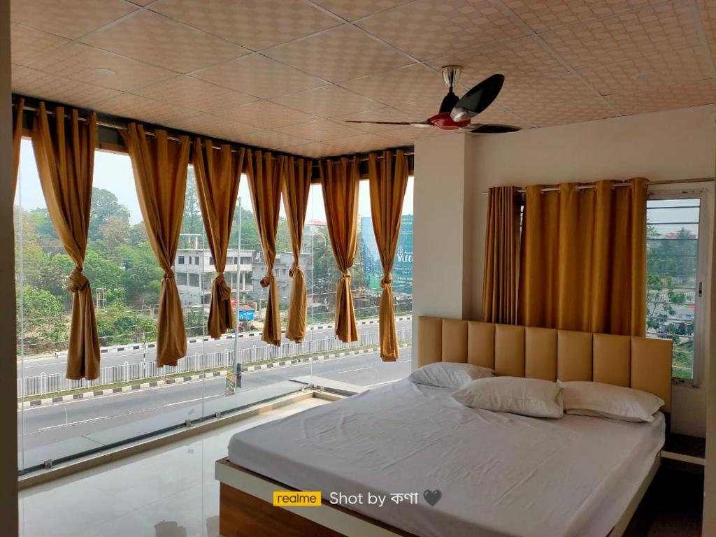 a bedroom with a bed and a large window at Mayer Anchal in Bāghdogra