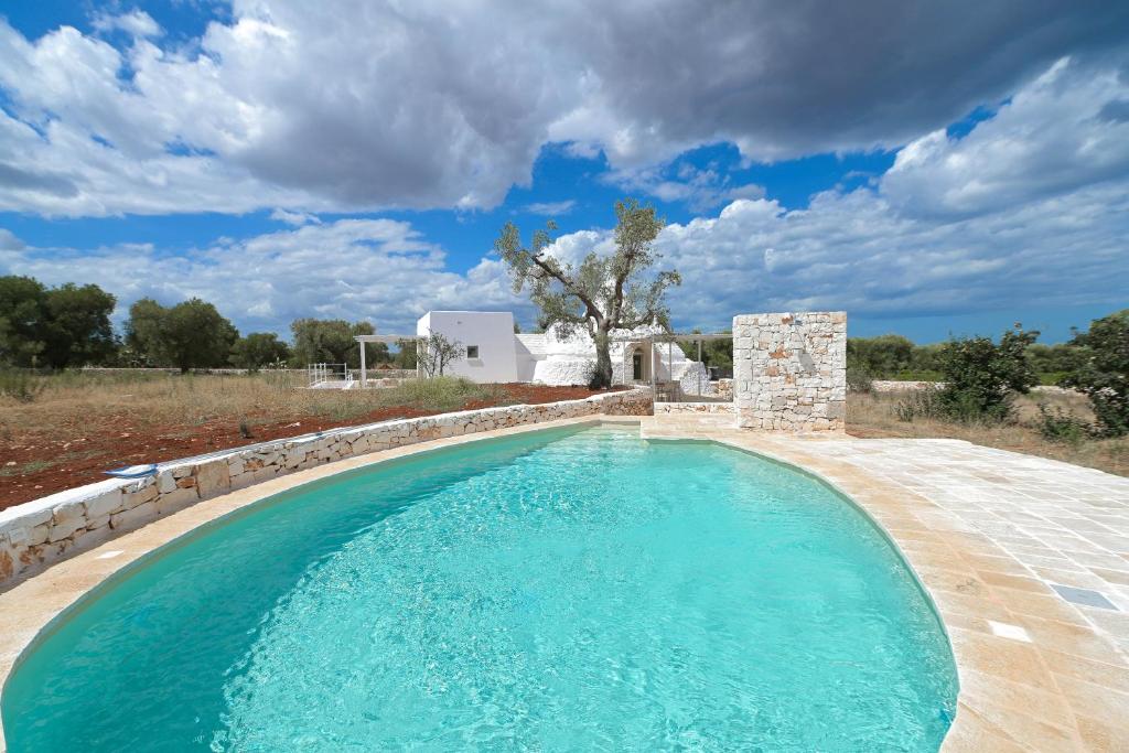 - une piscine avec un mur en pierre et de l'eau bleue dans l'établissement Trullo White Dream con Piscina, à Ostuni