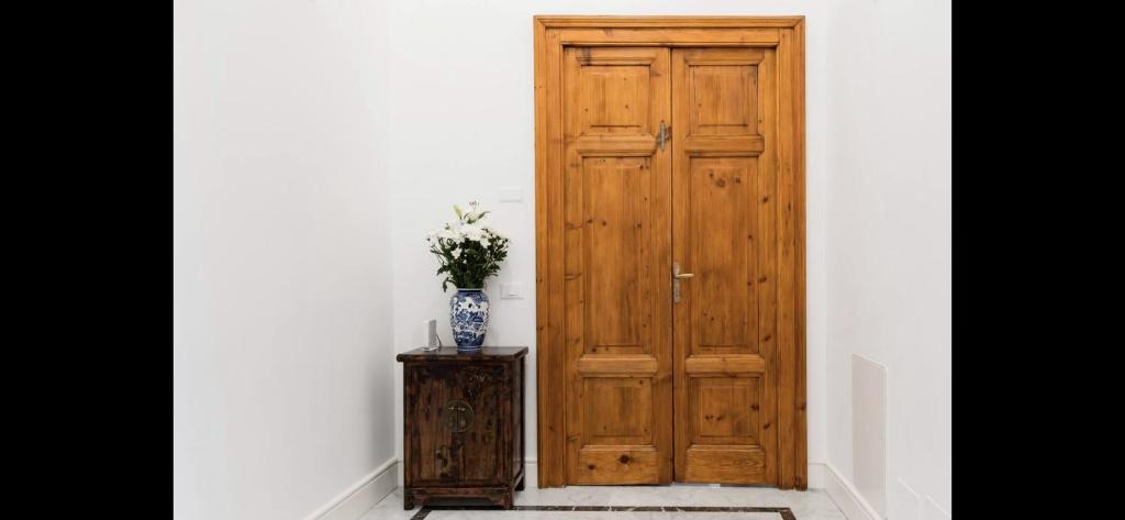 uma porta de madeira com um vaso de flores sobre uma mesa em Esquiline Suites em Roma