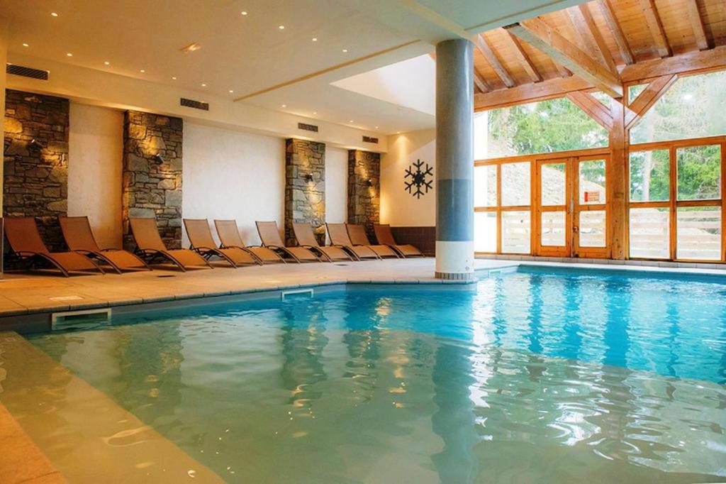 uma piscina num hotel com cadeiras num quarto em Appartement Les Coches em La Plagne Tarentaise