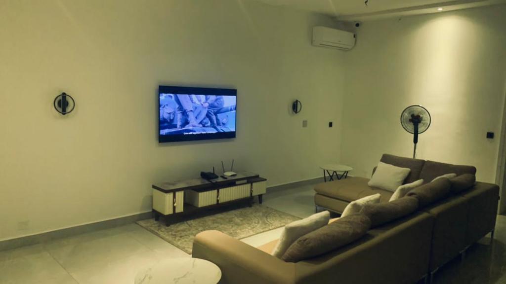 sala de estar con sofá y TV de pantalla plana en EKOH'S PLACE, en Abuja