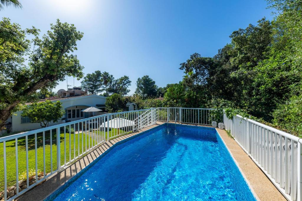 una piscina con una valla blanca y árboles en Casa Familia, en Sa Pobla