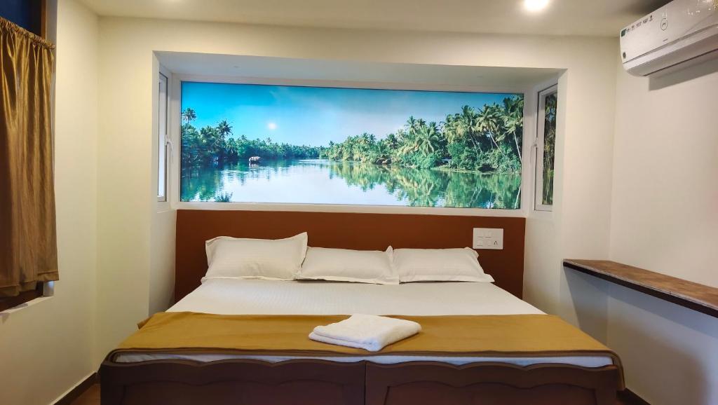 a bed in a room with a large painting on the wall at Ambadi's villa -Lake view resort in Pallipuram