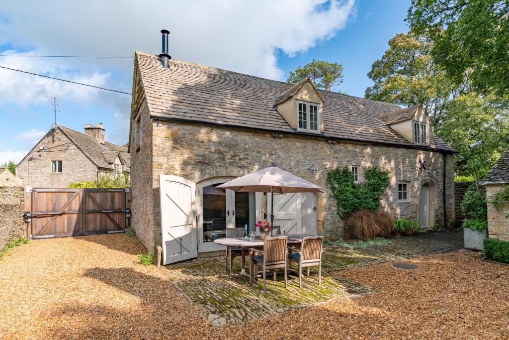 an old stone house with a table and chairs at Coach House, Cold Aston in Bourton on the Water