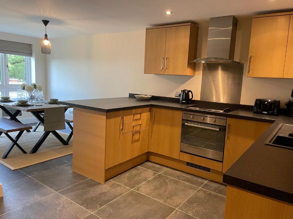 a kitchen with wooden cabinets and a dining table at 2 Cherry Tree Cottages in Stock