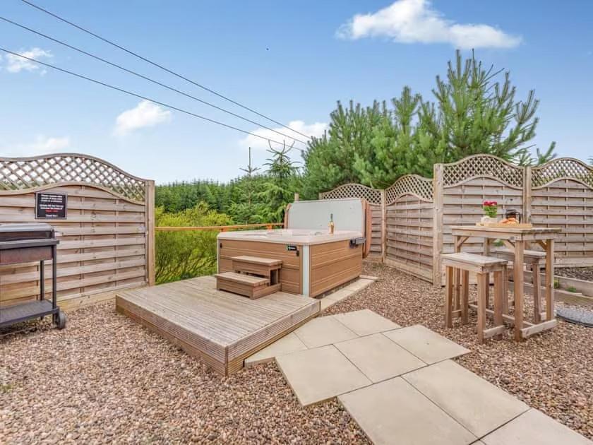 a backyard with a grill and a table and chairs at Lochinvar - Clydesdale Log Cabin with Hot Tub in Airdrie