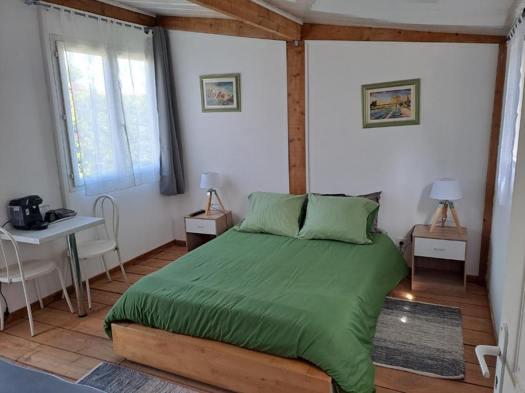 ein Schlafzimmer mit einem Bett mit einer grünen Bettdecke in der Unterkunft Chambre basilic 2p, 2 nuits max, dans petit chalet 6km du festival de piano de la roque d'anthéron in Rognes