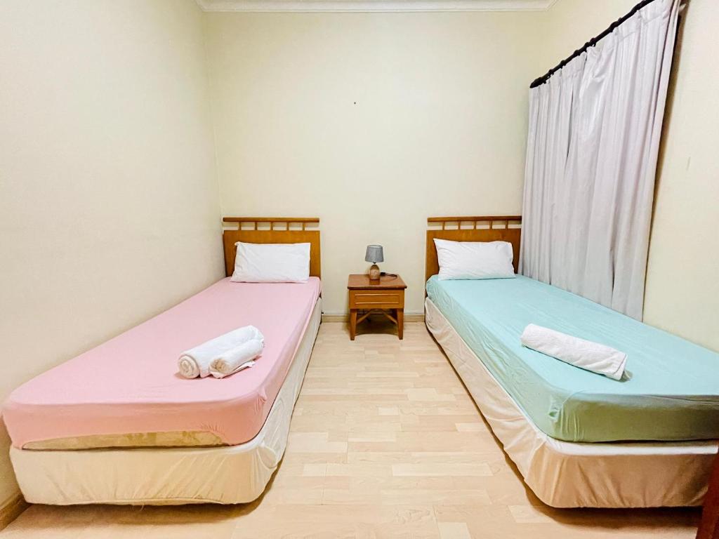 twee bedden naast elkaar in een kamer bij D MARINE’ HOMESTAY in Kota Kinabalu