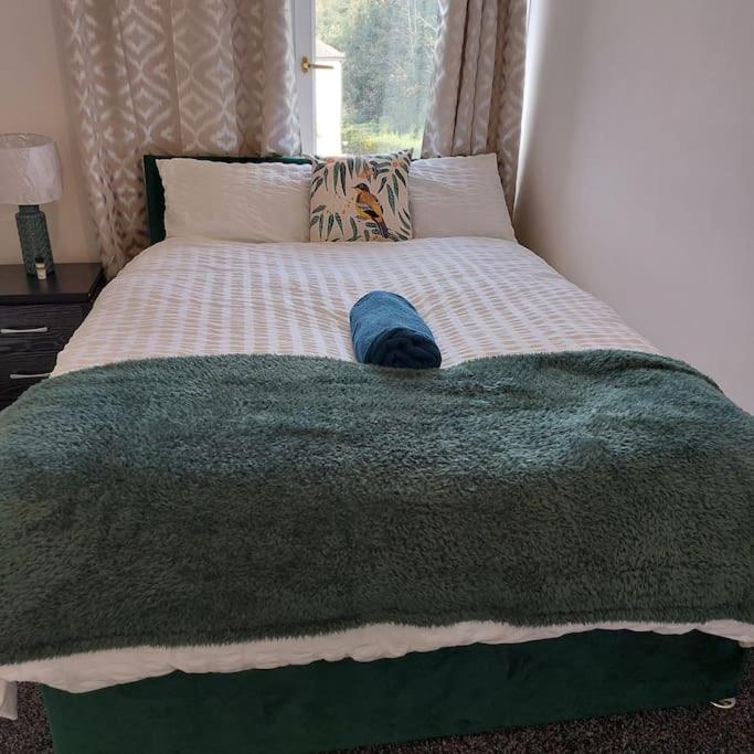 a bed with a green blanket with a hat on it at 4 Double Bedroom House in Accrington sleeps 6 in Accrington