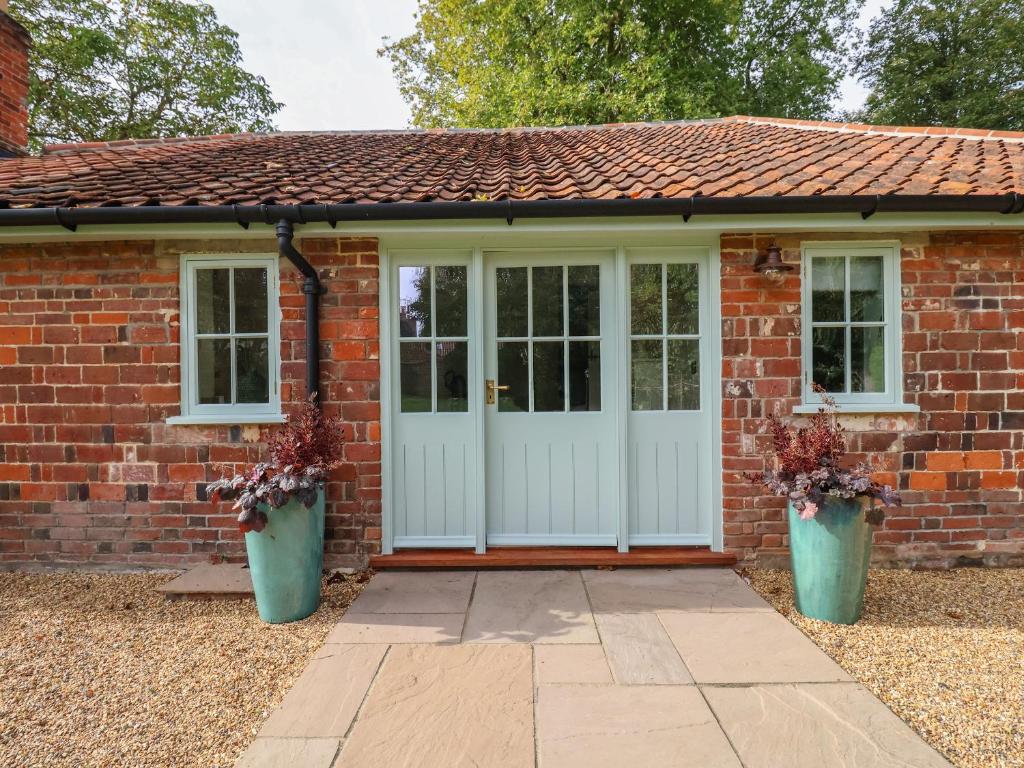 a brick house with a white door and windows at Rookery Cottage in Saxmundham