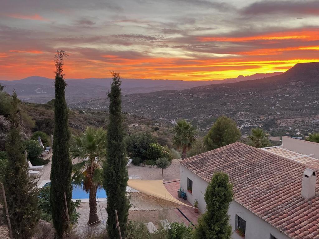 uma vista para uma casa com um pôr-do-sol ao fundo em Boutique B&B El Refugio em Alcaucín