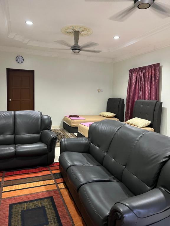 sala de estar con sofá de cuero y cama en Tok Wan Roomstay en Kampong Banggol Binjai