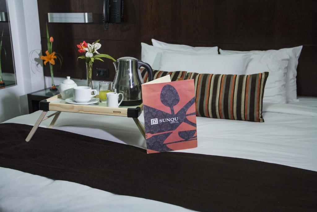 Una cama con una bandeja con una mesa y un set de té. en Hotel Sunqu, en Lima