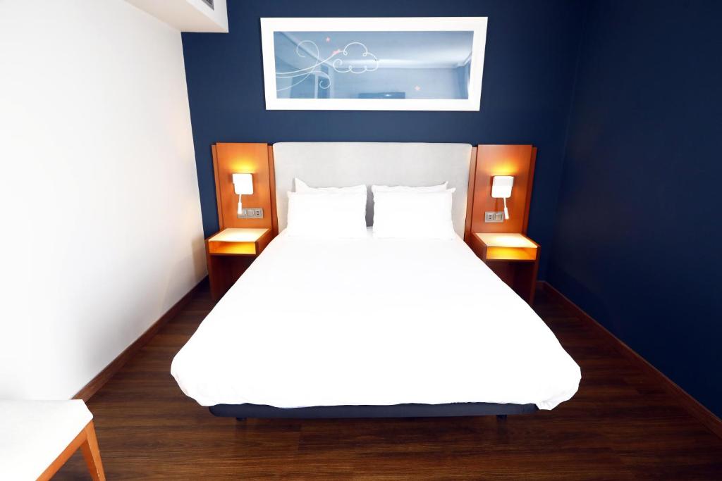 sypialnia z białym łóżkiem i niebieską ścianą w obiekcie Travelodge Madrid Coslada Aeropuerto w mieście Coslada