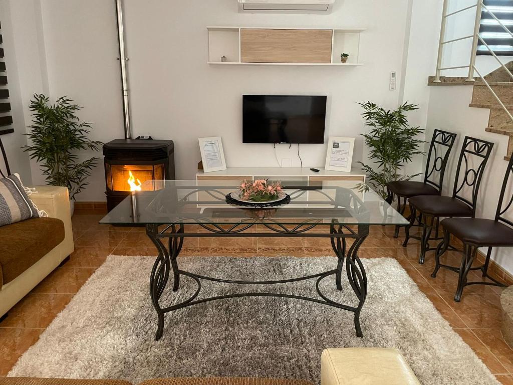 sala de estar con mesa de cristal y chimenea en ALOJAMIENTO Rural AVD SIERRA MÁGINA, en Carchelejo